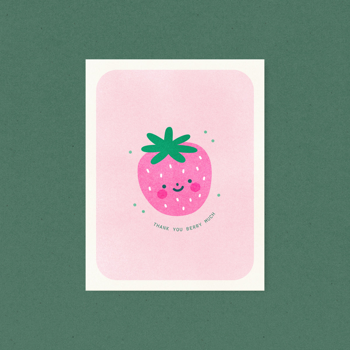 Whimsical risograph thank you card printed with fluorescent pink and green vegetable-based inks, featuring a cute smiling strawberry with bright pink cheeks and a leafy green top on a pink background. The words "Thank You Berry Much" curve beneath it, and a kraft envelope is included. A delightful handmade card from Seattle, WA by Minna May.