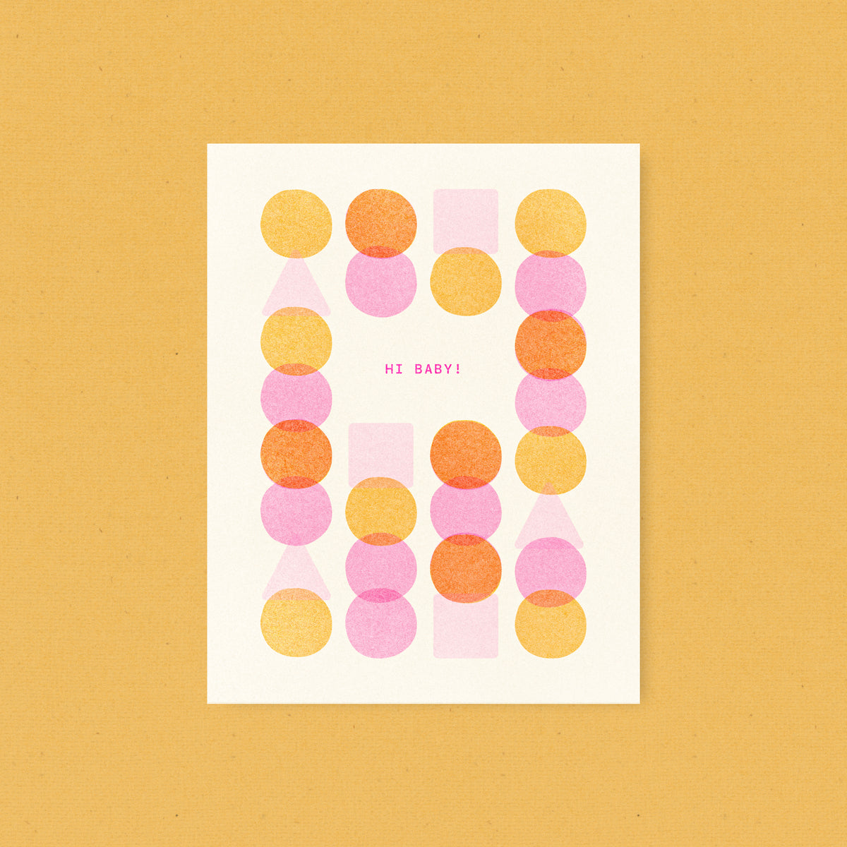 Whimsical risograph baby greeting card printed with fluorescent pink and yellow vegetable-based inks, featuring a playful and modern pattern of overlapping circles, squares, and triangles on cream paper. The words "Hi Baby!" sit in the center, and a kraft envelope is included. A delightful handmade new baby card from Seattle, WA by Minna May.